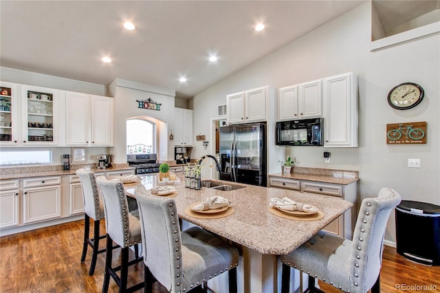 kitchen with a kitchen island with sink, appliances with stainless steel finishes, a breakfast bar, and a sink