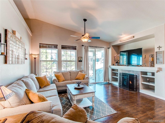 living area featuring ceiling fan, wood finished floors, a tile fireplace, and vaulted ceiling