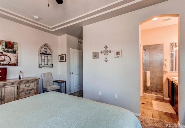 bedroom featuring connected bathroom, arched walkways, visible vents, and stone tile flooring