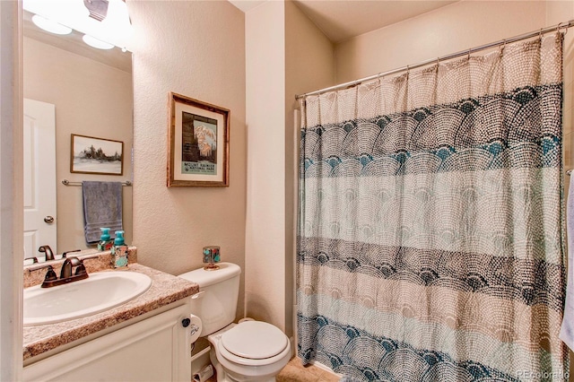 full bath with vanity, curtained shower, toilet, and a textured wall