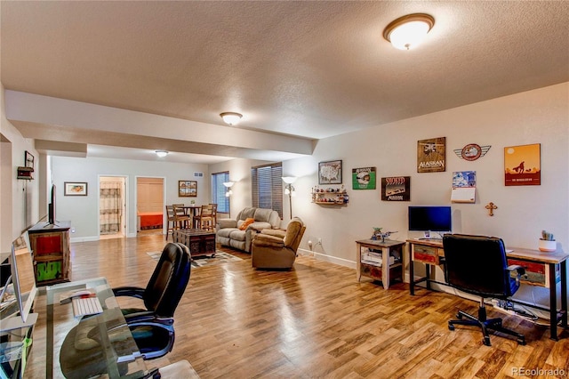 home office featuring baseboards, a textured ceiling, and light wood-style floors