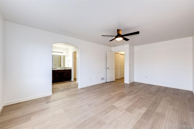 unfurnished bedroom with light wood-type flooring, ensuite bath, and ceiling fan