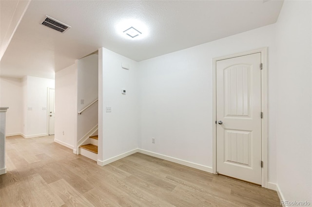 spare room featuring light wood-type flooring and a textured ceiling