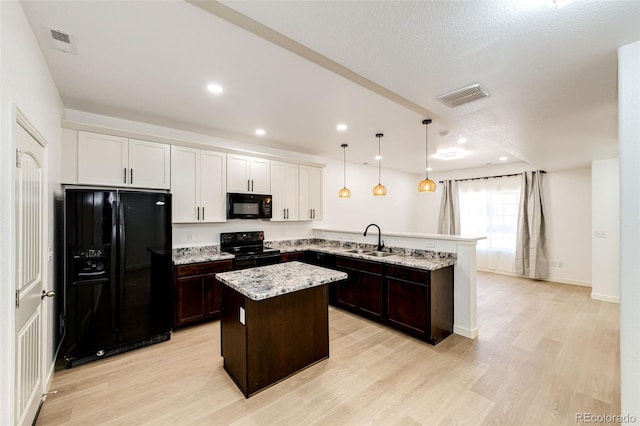 kitchen with a center island, light hardwood / wood-style flooring, kitchen peninsula, pendant lighting, and black appliances