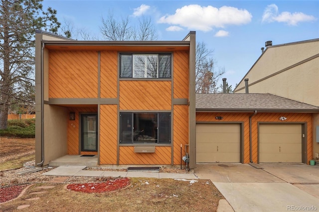 view of front of home featuring a garage, concrete driveway, and a shingled roof