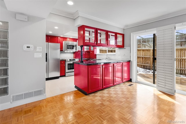 kitchen featuring visible vents, dark brown cabinets, decorative backsplash, a peninsula, and stainless steel appliances