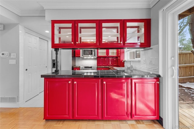 kitchen featuring visible vents, appliances with stainless steel finishes, a peninsula, crown molding, and decorative backsplash