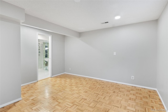 empty room featuring visible vents, a textured ceiling, and baseboards