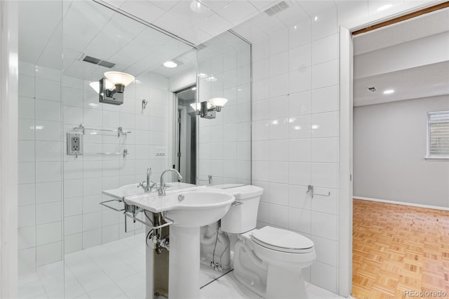 bathroom featuring tile walls, toilet, and visible vents