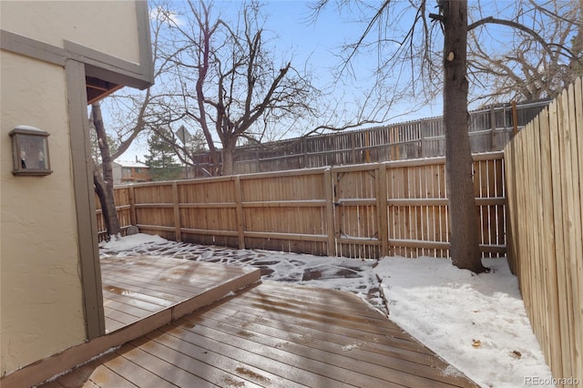 snow covered deck with a fenced backyard