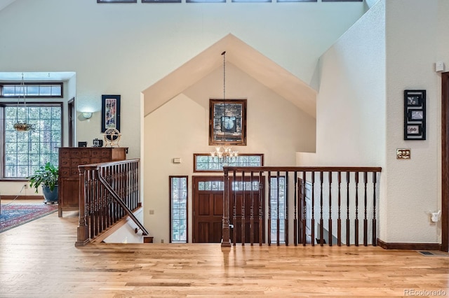 foyer entrance featuring a notable chandelier, high vaulted ceiling, and wood finished floors