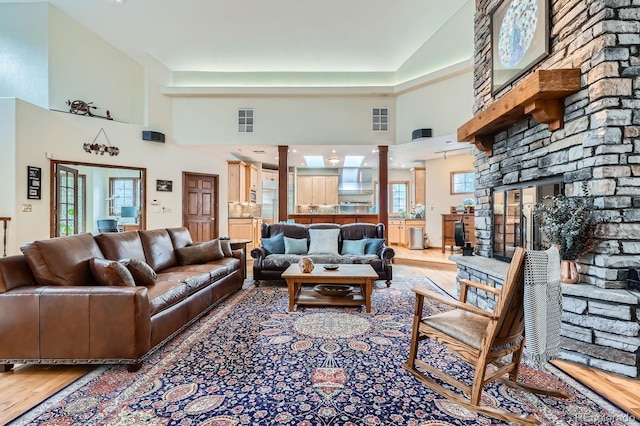 living room with visible vents, decorative columns, a towering ceiling, and wood finished floors