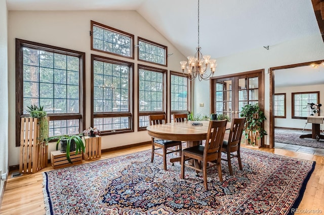 dining area with a chandelier, light wood-style flooring, high vaulted ceiling, and a healthy amount of sunlight