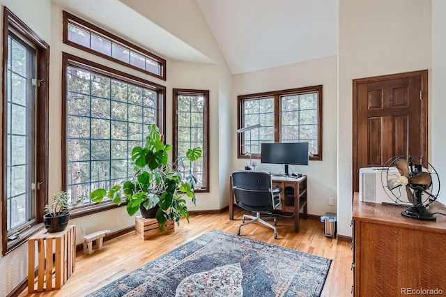 office area featuring baseboards, light wood-style flooring, and vaulted ceiling