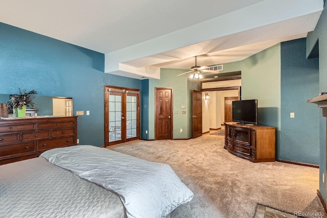 bedroom featuring visible vents, baseboards, light colored carpet, a textured wall, and a ceiling fan