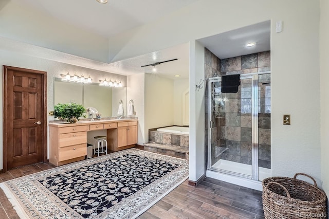 full bath with vanity, wood finished floors, baseboards, a shower stall, and a bath