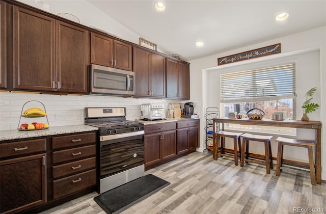 2734 Grand Prix Ct, Colorado Springs, CO 80922 - kitchen with stainless steel appliances, decorative backsplash, light wood-style flooring, dark brown cabinetry, and recessed lighting