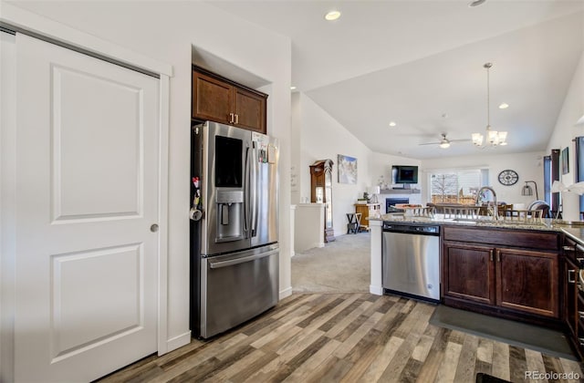 2734 Grand Prix Ct, Colorado Springs, CO 80922 - kitchen featuring appliances with stainless steel finishes, a sink, light wood-type flooring, vaulted ceiling, and open floor plan