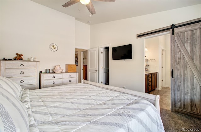 2734 Grand Prix Ct, Colorado Springs, CO 80922 - bedroom with a barn door, carpet flooring, ensuite bathroom, and ceiling fan