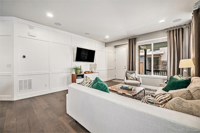 living room with dark wood-style flooring, recessed lighting, visible vents, and a decorative wall