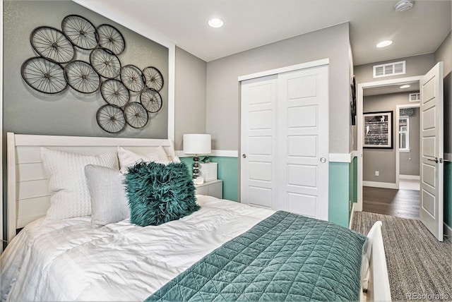 bedroom with a closet, wood finished floors, visible vents, and recessed lighting