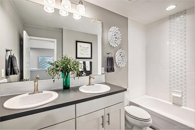 bathroom with toilet, double vanity, shower / washtub combination, and a sink