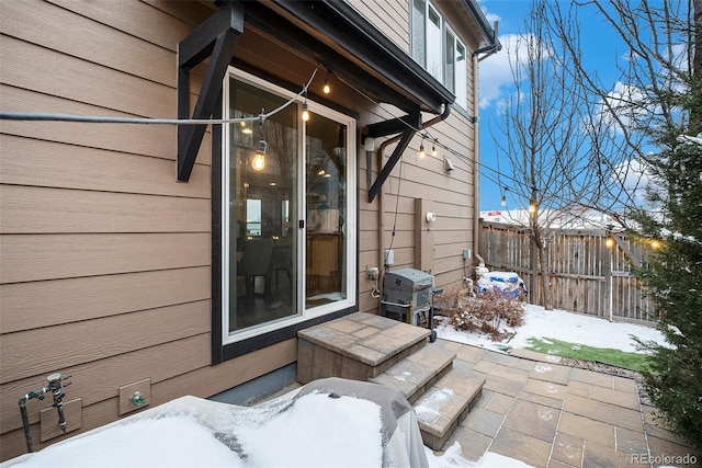 snow covered patio with fence and area for grilling