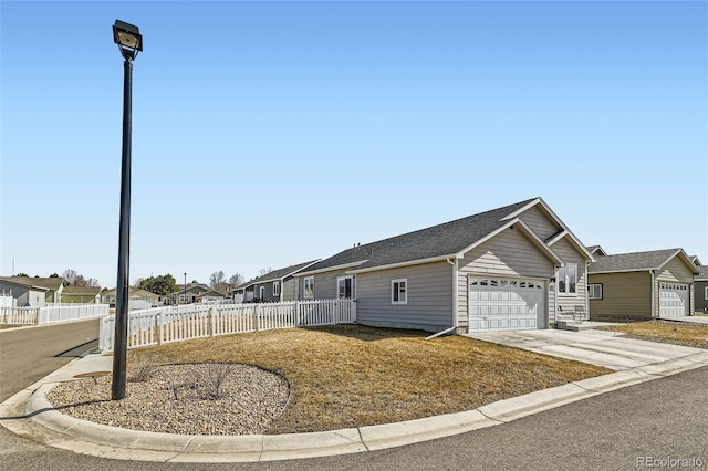 view of front of property featuring a residential view, concrete driveway, and fence