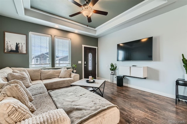 living area featuring dark wood-style floors, baseboards, a raised ceiling, and a ceiling fan