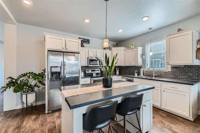 kitchen featuring stainless steel appliances, dark countertops, a sink, and decorative backsplash