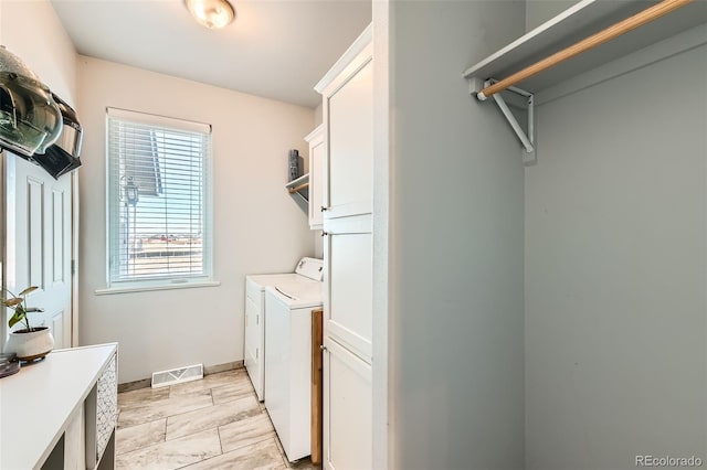 clothes washing area featuring independent washer and dryer, visible vents, cabinet space, and baseboards