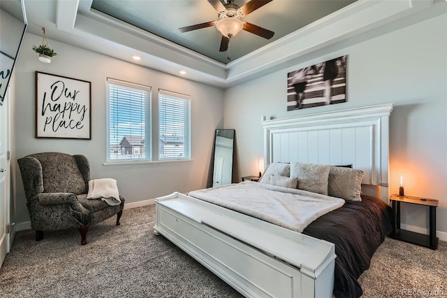 carpeted bedroom with a ceiling fan, a raised ceiling, and baseboards