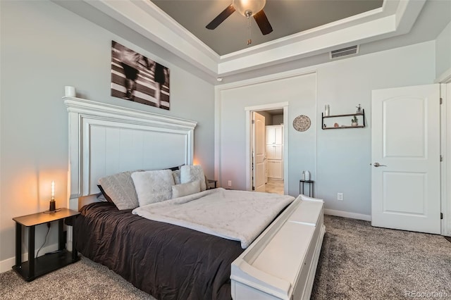 bedroom featuring light carpet, a tray ceiling, visible vents, and baseboards