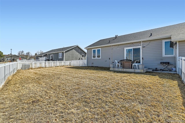 back of house with a fenced backyard and a yard