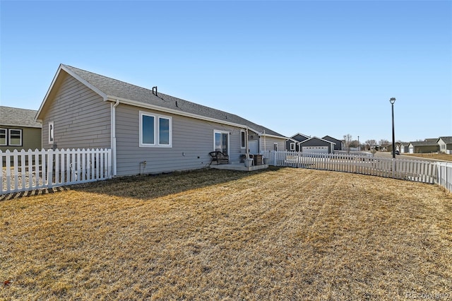 back of house with a fenced backyard, a lawn, and a patio