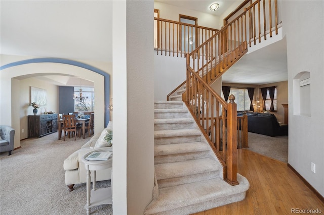 9684 W Long Dr, Littleton, CO 80123 - staircase featuring arched walkways, carpet, a high ceiling, a chandelier, and wood finished floors