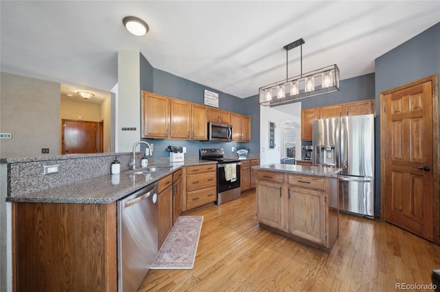 9684 W Long Dr, Littleton, CO 80123 - kitchen featuring appliances with stainless steel finishes, a sink, a peninsula, dark stone countertops, and light wood finished floors