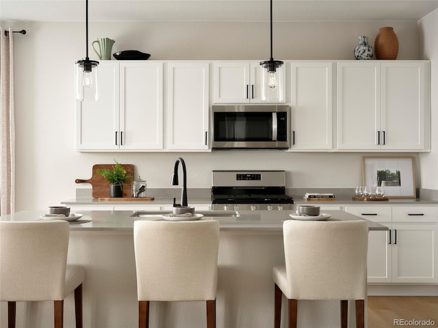 kitchen featuring stainless steel appliances, a breakfast bar area, and white cabinetry