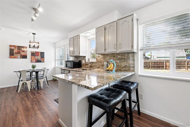 11041 Newland St, Westminster, CO 80020 - kitchen featuring black microwave, dark wood finished floors, a kitchen breakfast bar, and baseboards