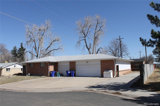 view of front of home with brick siding, driveway, a garage, and fence