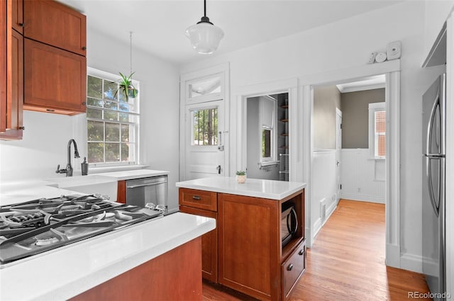 1038 E 4th Ave, Denver, CO 80218 - kitchen featuring stainless steel appliances, brown cabinets, light countertops, a wainscoted wall, and light wood-style flooring