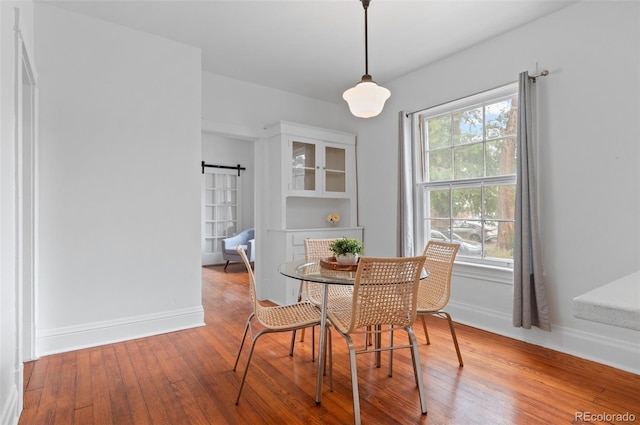1038 E 4th Ave, Denver, CO 80218 - dining area featuring hardwood / wood-style floors, a barn door, and baseboards