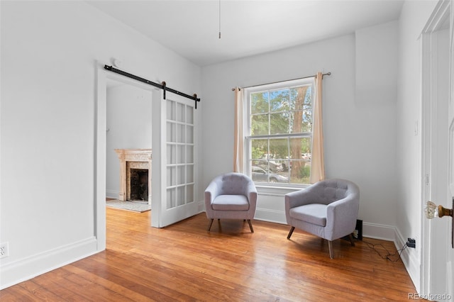 1038 E 4th Ave, Denver, CO 80218 - sitting room with light wood-style floors, a brick fireplace, a barn door, and baseboards