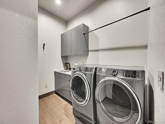 6736 S Flanders Ct, Aurora, CO 80016 - laundry room featuring a textured wall, separate washer and dryer, light wood-type flooring, cabinet space, and baseboards