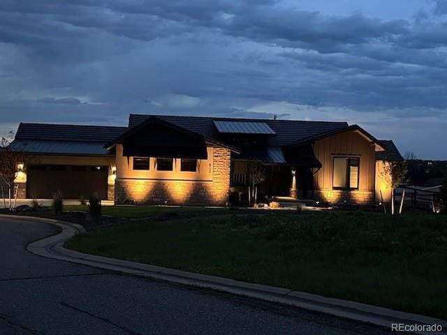 6736 S Flanders Ct, Aurora, CO 80016 - ranch-style home featuring a front yard, stone siding, an attached garage, driveway, and solar panels