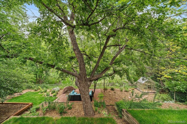 116 Monarch St, Louisville, CO 80027 - fenced backyard with a vegetable garden, an exterior structure, and an outbuilding