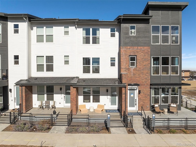 view of front of property featuring fence private yard, a patio area, and brick siding