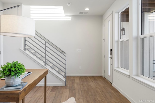 foyer with recessed lighting, wood finished floors, visible vents, baseboards, and stairs