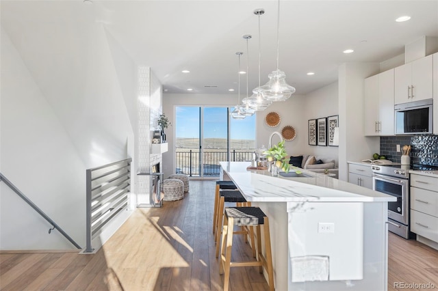 kitchen featuring a kitchen breakfast bar, decorative light fixtures, a center island, stainless steel appliances, and white cabinetry