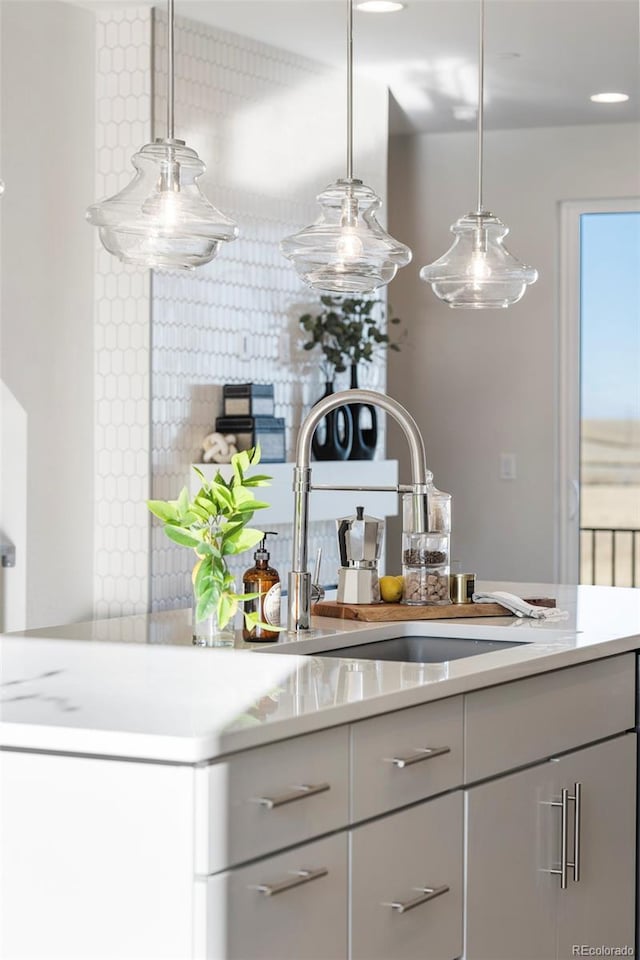 kitchen with a sink, hanging light fixtures, gray cabinets, and light countertops